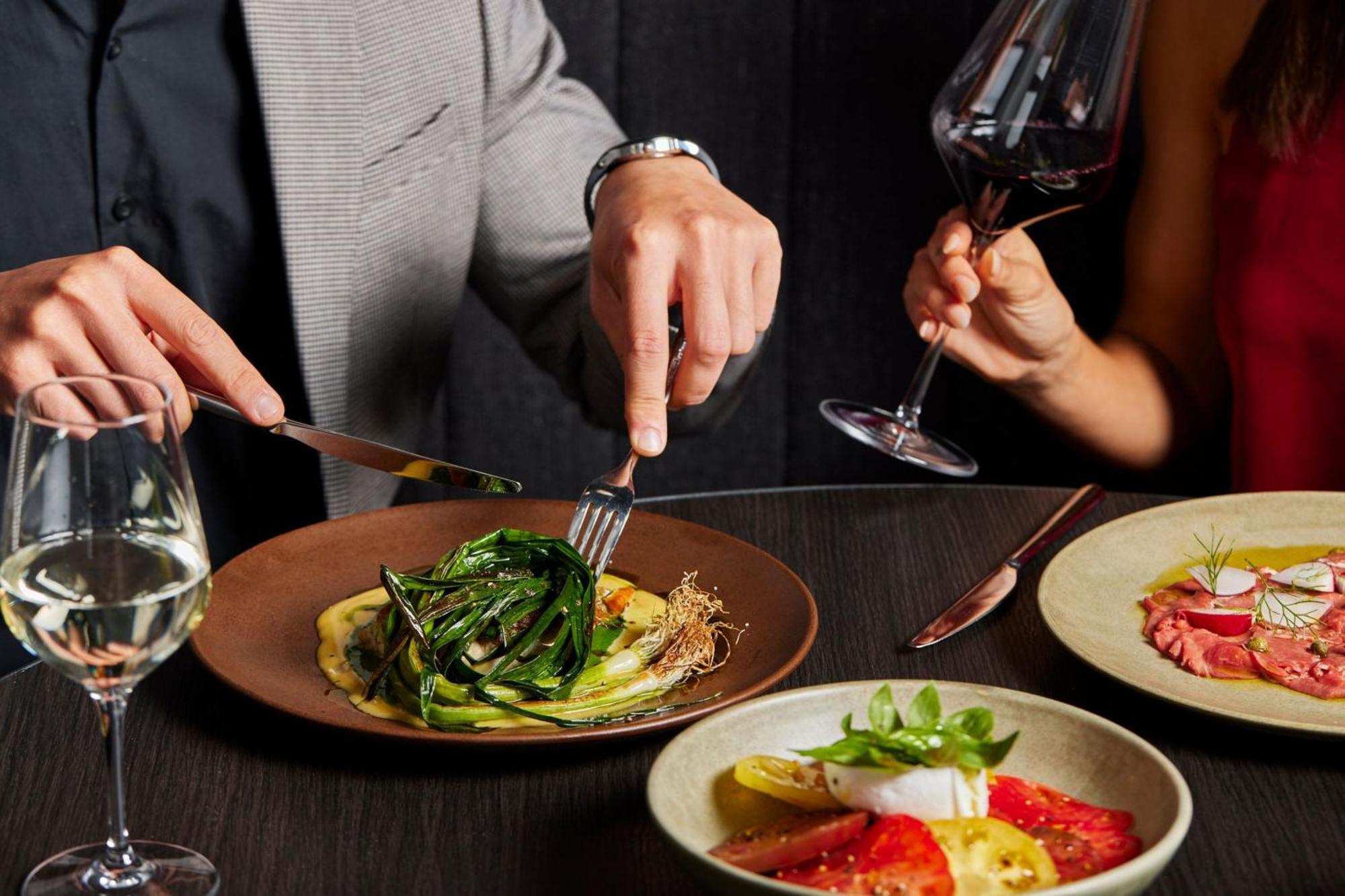 Melbourne Marriott Hotel Docklands Exterior foto A man using a knife and fork to cut into a meal